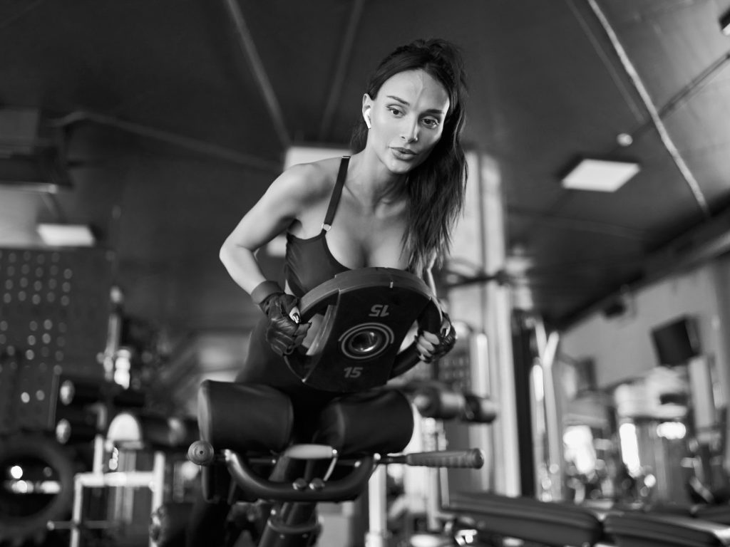 Woman doing hyperextension with weight, black and white.